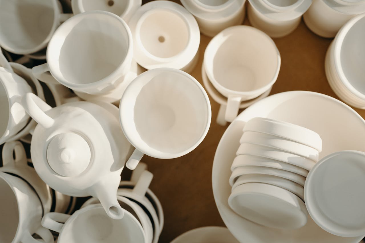 Elegant display of white ceramic cups, teapots, and plates viewed from above.